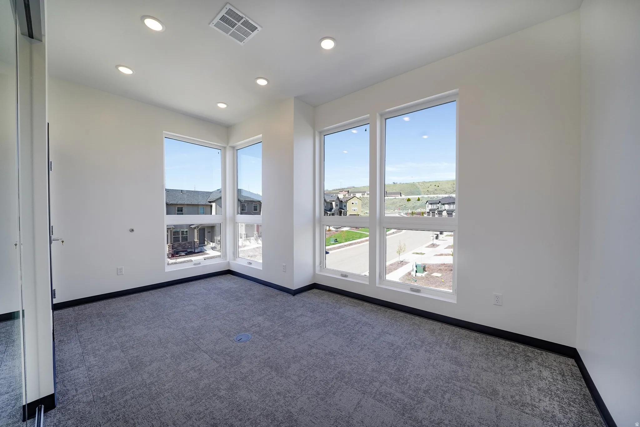 Empty room with dark colored carpet and recessed lighting