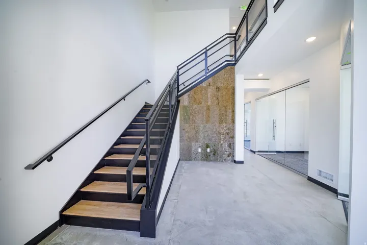 Stairway featuring a high ceiling, concrete floors, and recessed lighting