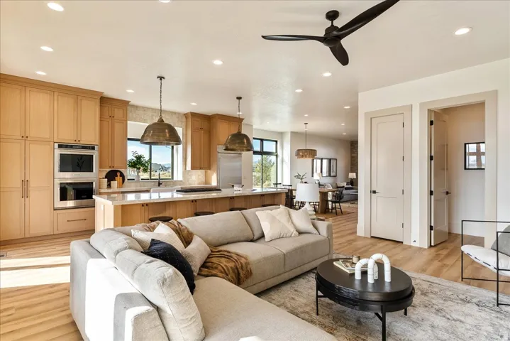 Living room with light wood-style flooring, ceiling fan, and recessed lighting