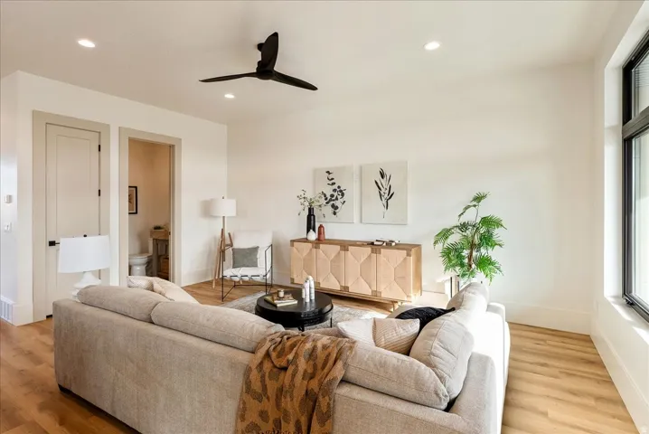 Living area with a ceiling fan, light wood finished floors, and recessed lighting