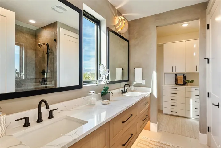 Bathroom with double vanity, a tile shower, and recessed lighting
