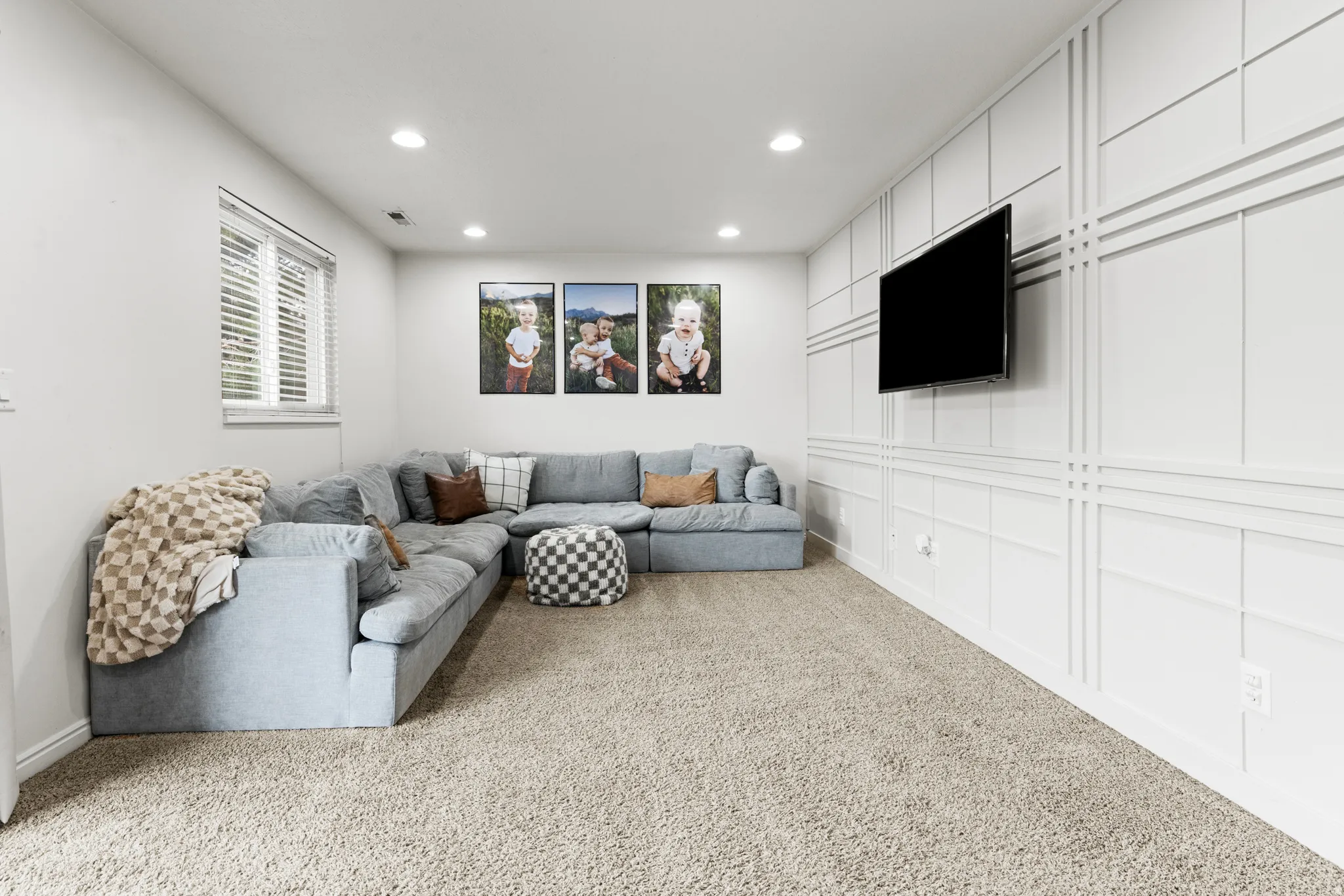 Living area with light colored carpet, recessed lighting, and a decorative wall