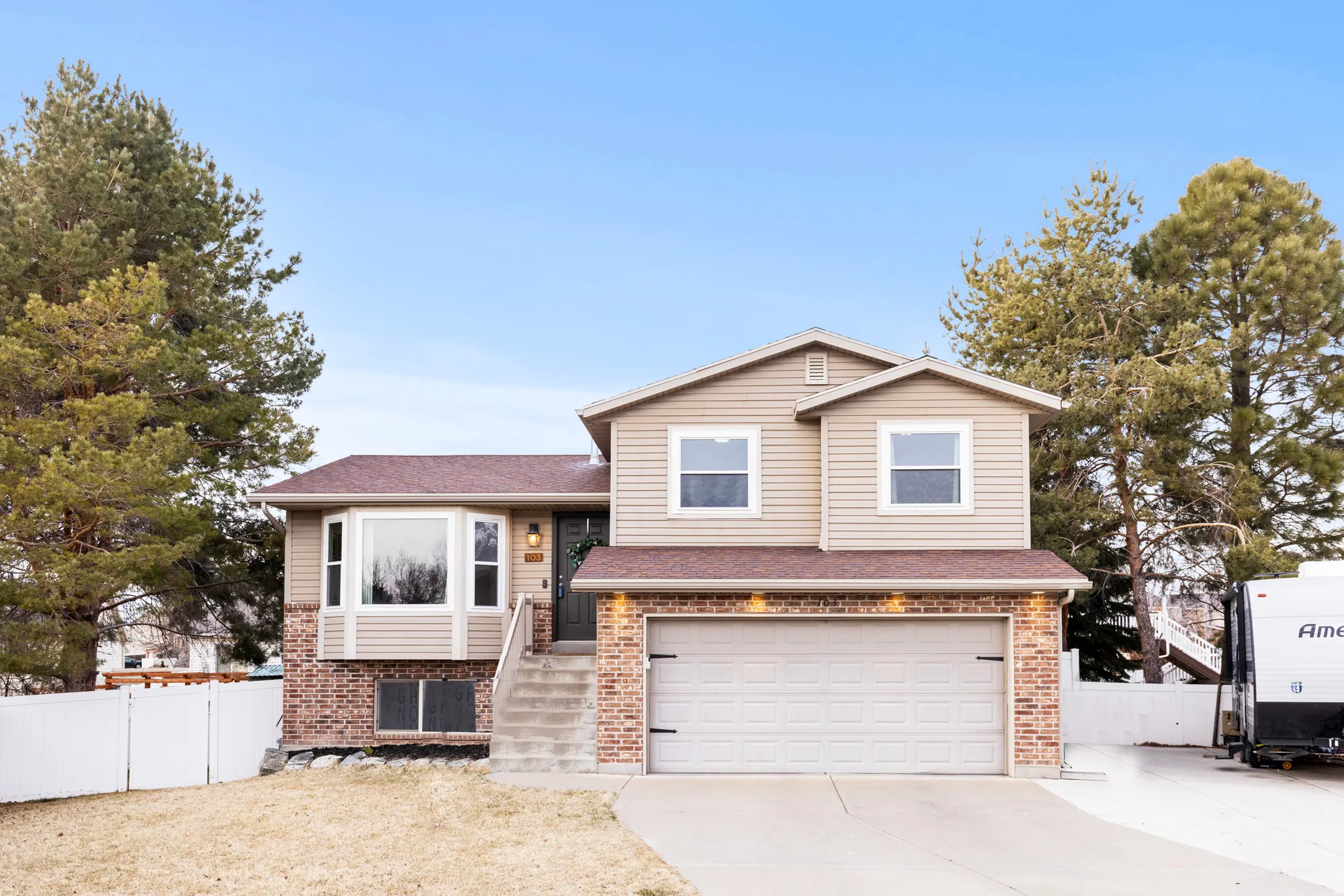 Split level home featuring concrete driveway, brick siding, a garage, and a shingled roof