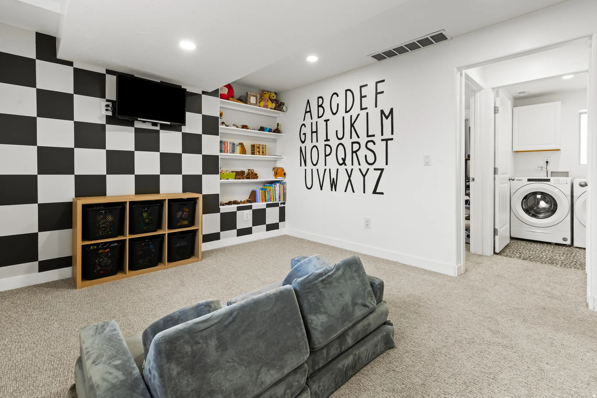 Living area featuring light carpet, washing machine and dryer, recessed lighting, and an accent wall