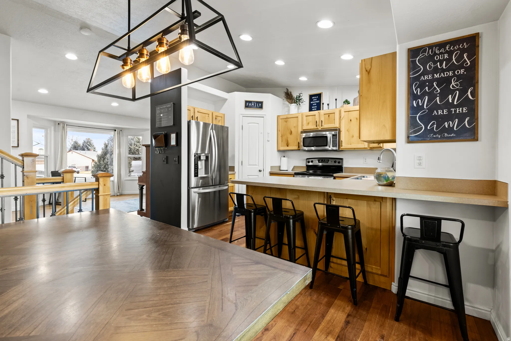 Kitchen featuring a kitchen bar, light countertops, stainless steel appliances, a peninsula, and decorative light fixtures