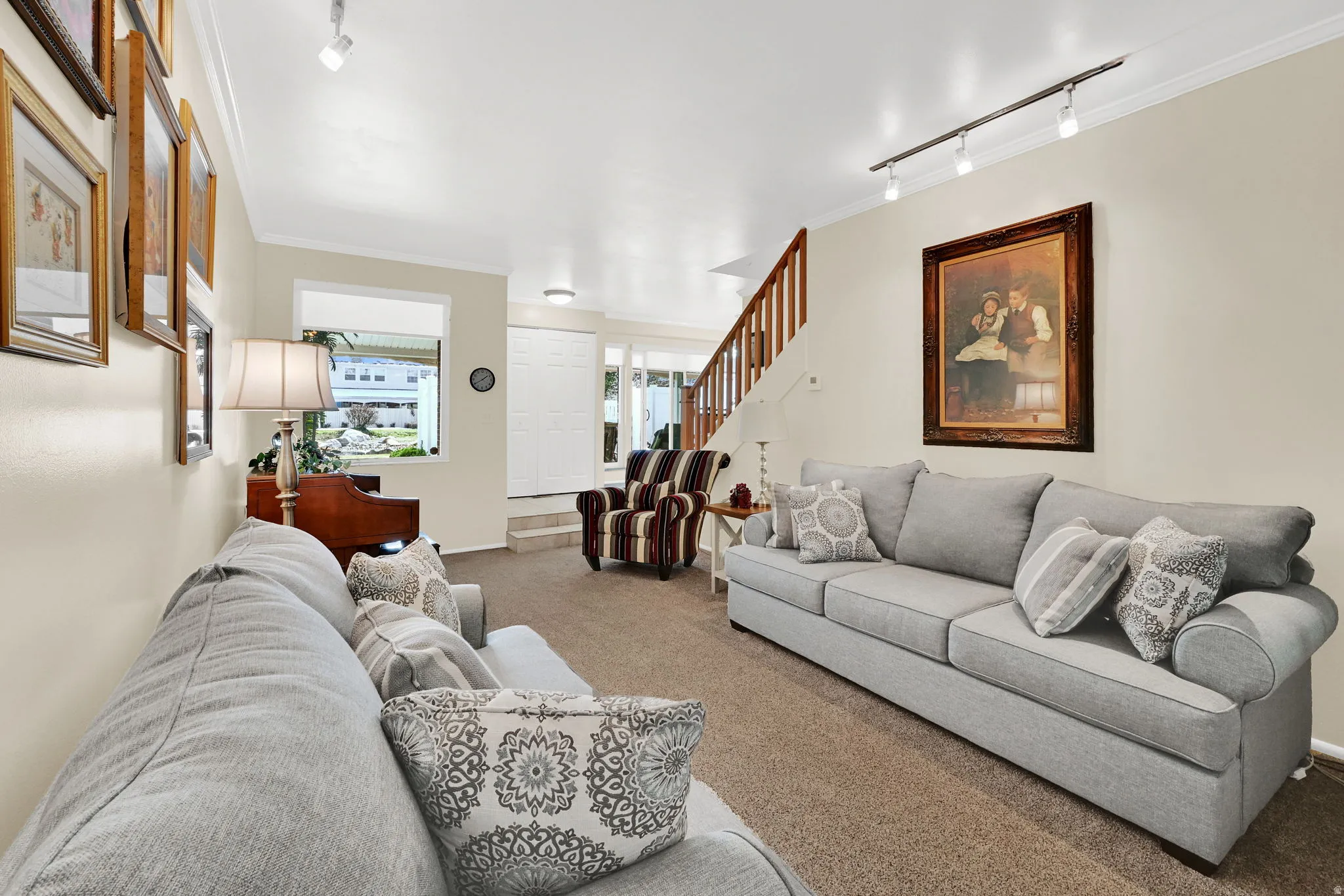 Living area with rail lighting, carpet, and ornamental molding