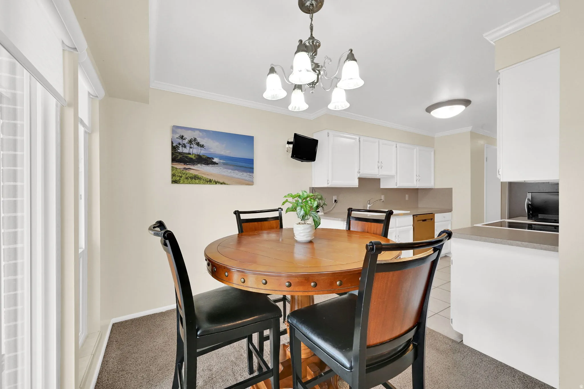 Dining area featuring light colored carpet, suspended lighting, and ornamental molding