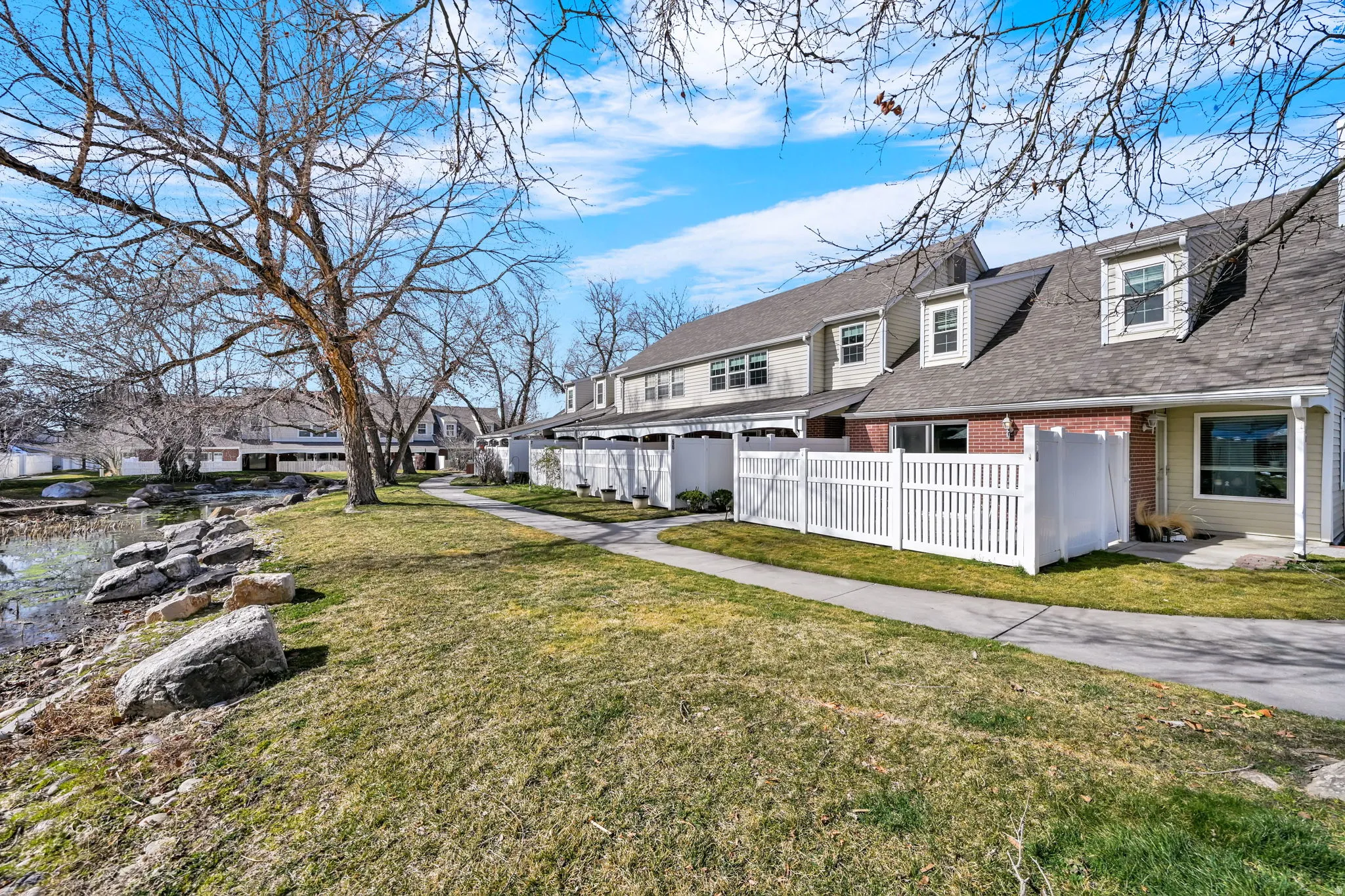View of front of house featuring a fenced front yard, roof with shingles, brick siding, and a residential view