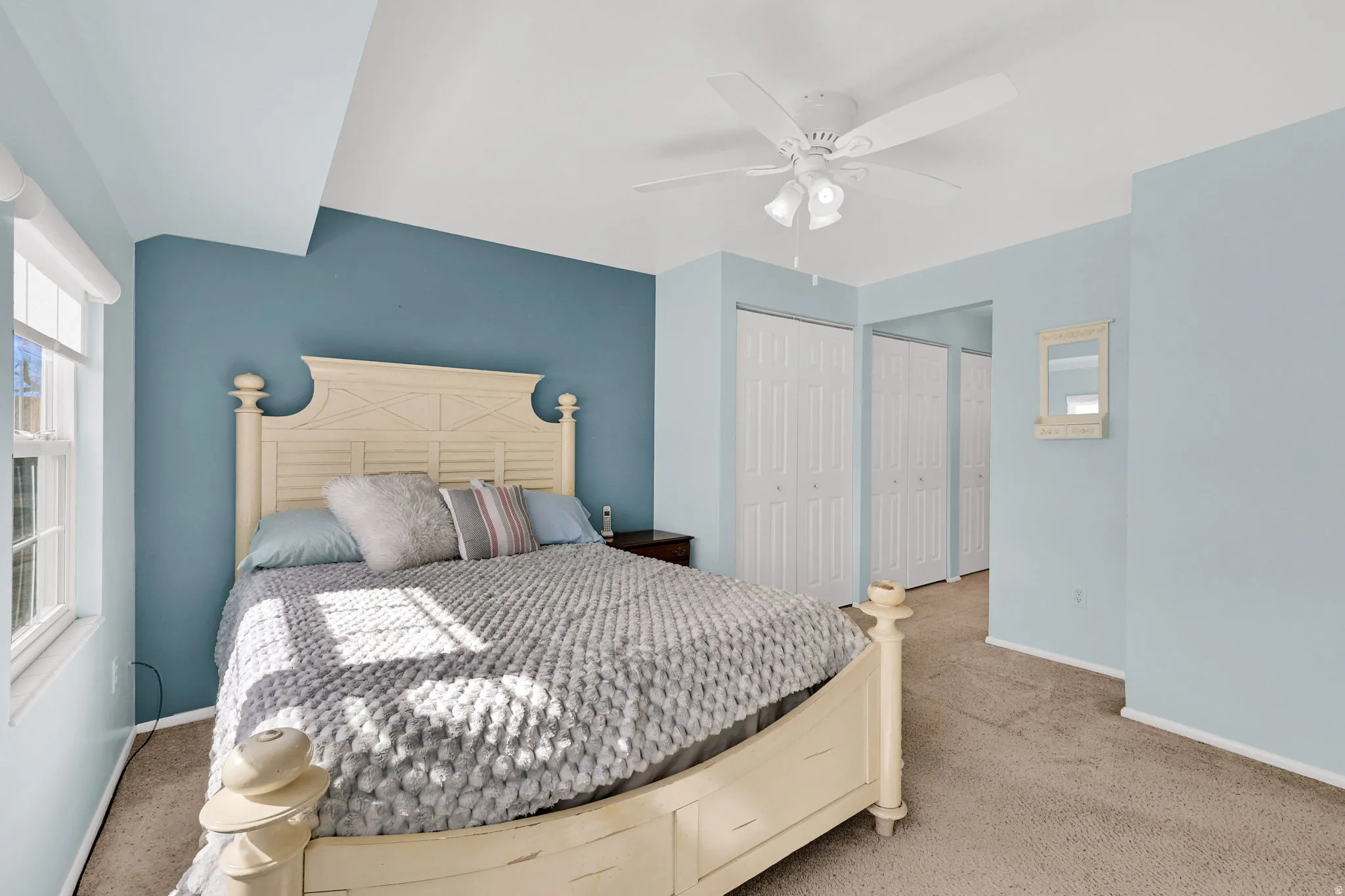 Carpeted bedroom with multiple closets and a ceiling fan
