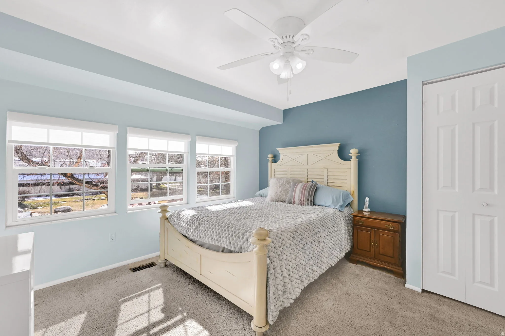Bedroom with ceiling fan, light colored carpet, and a closet