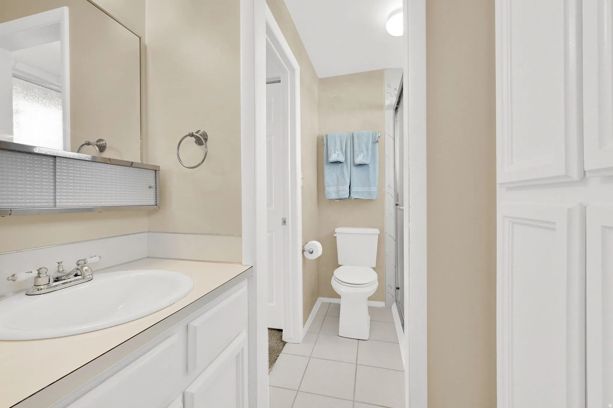 Full bath with vanity, light tile patterned floors, a stall shower, and a closet