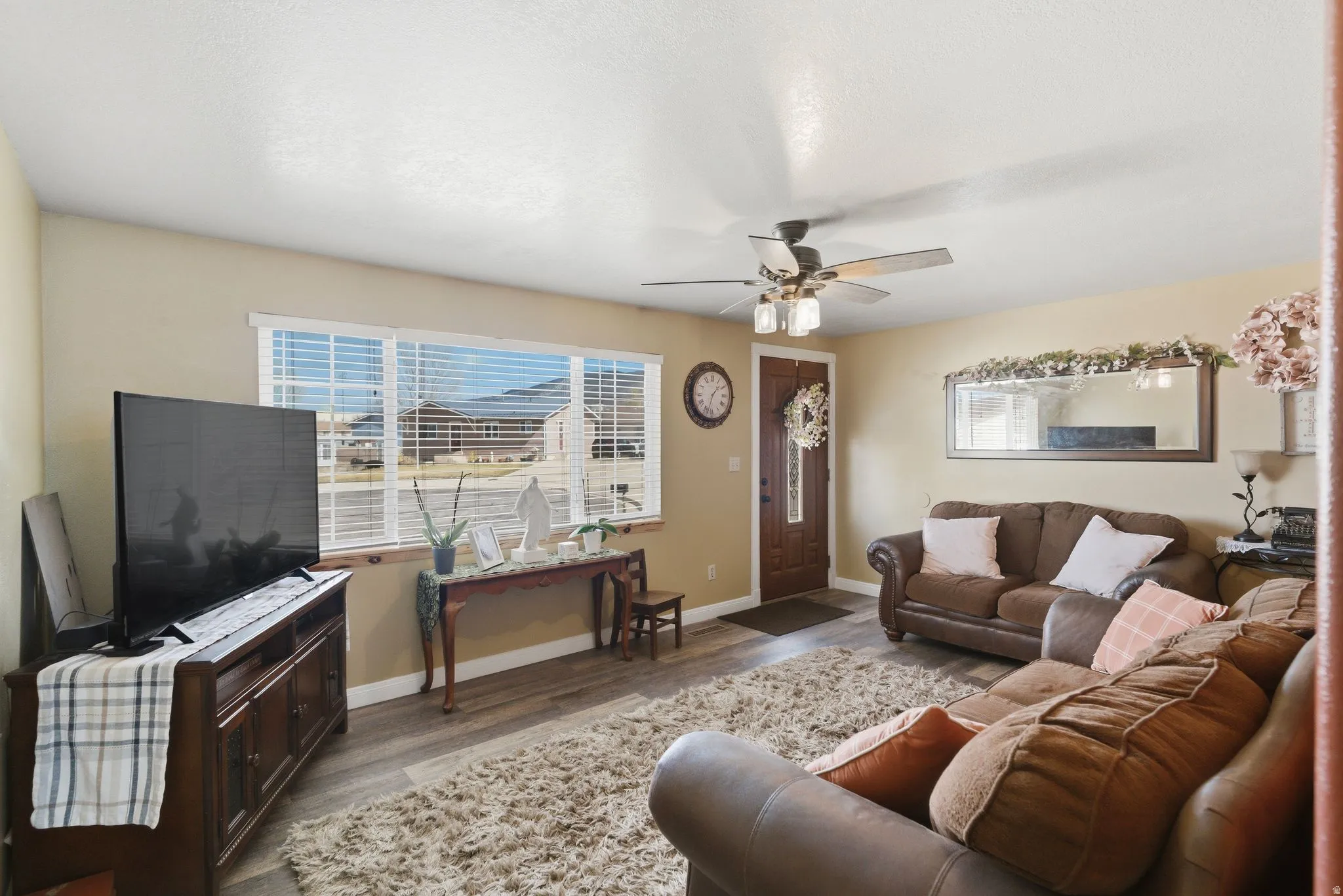 Living room with wood finished floors, a ceiling fan, and healthy amount of natural light