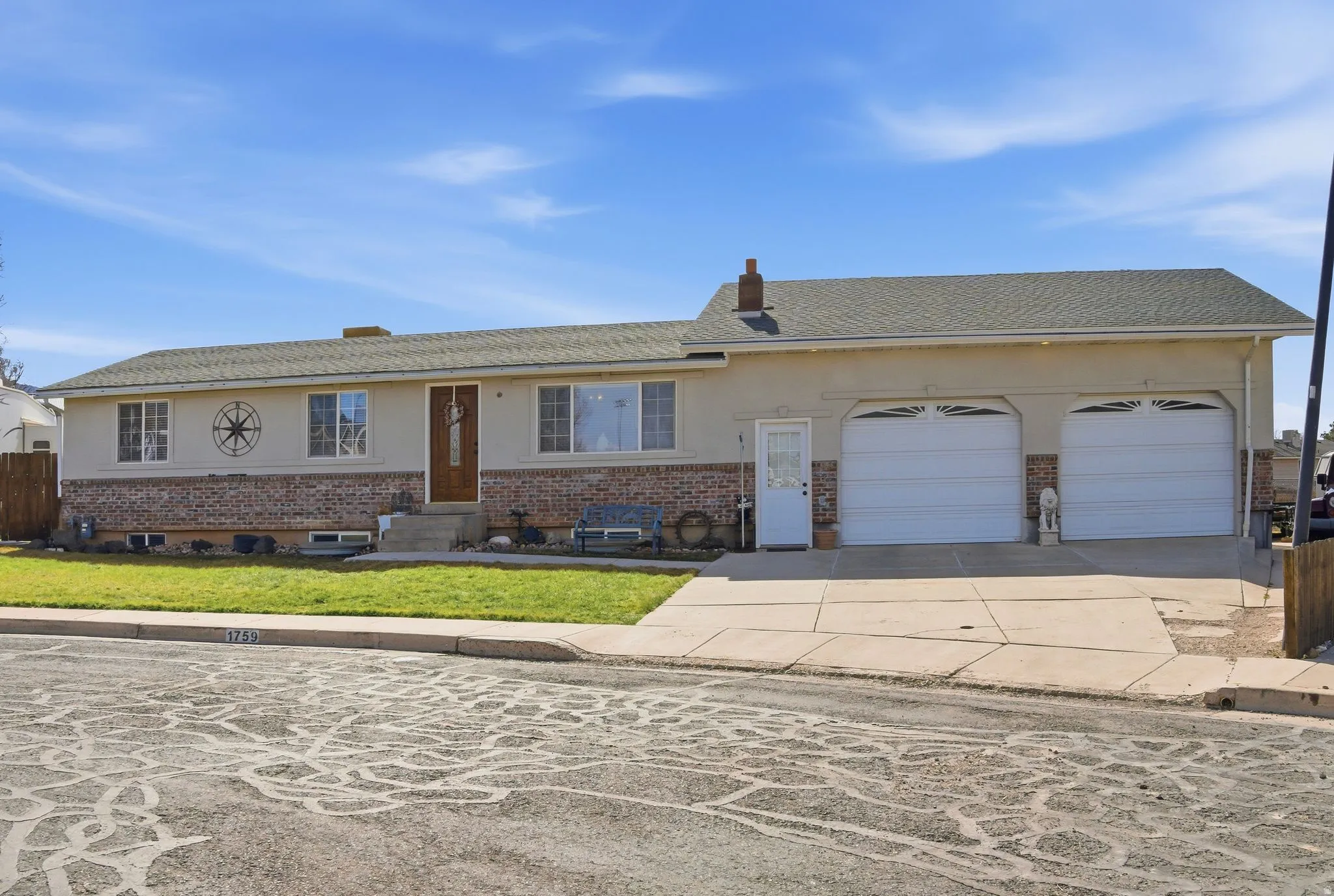 Single story home with concrete driveway, stucco siding, a garage, and brick siding