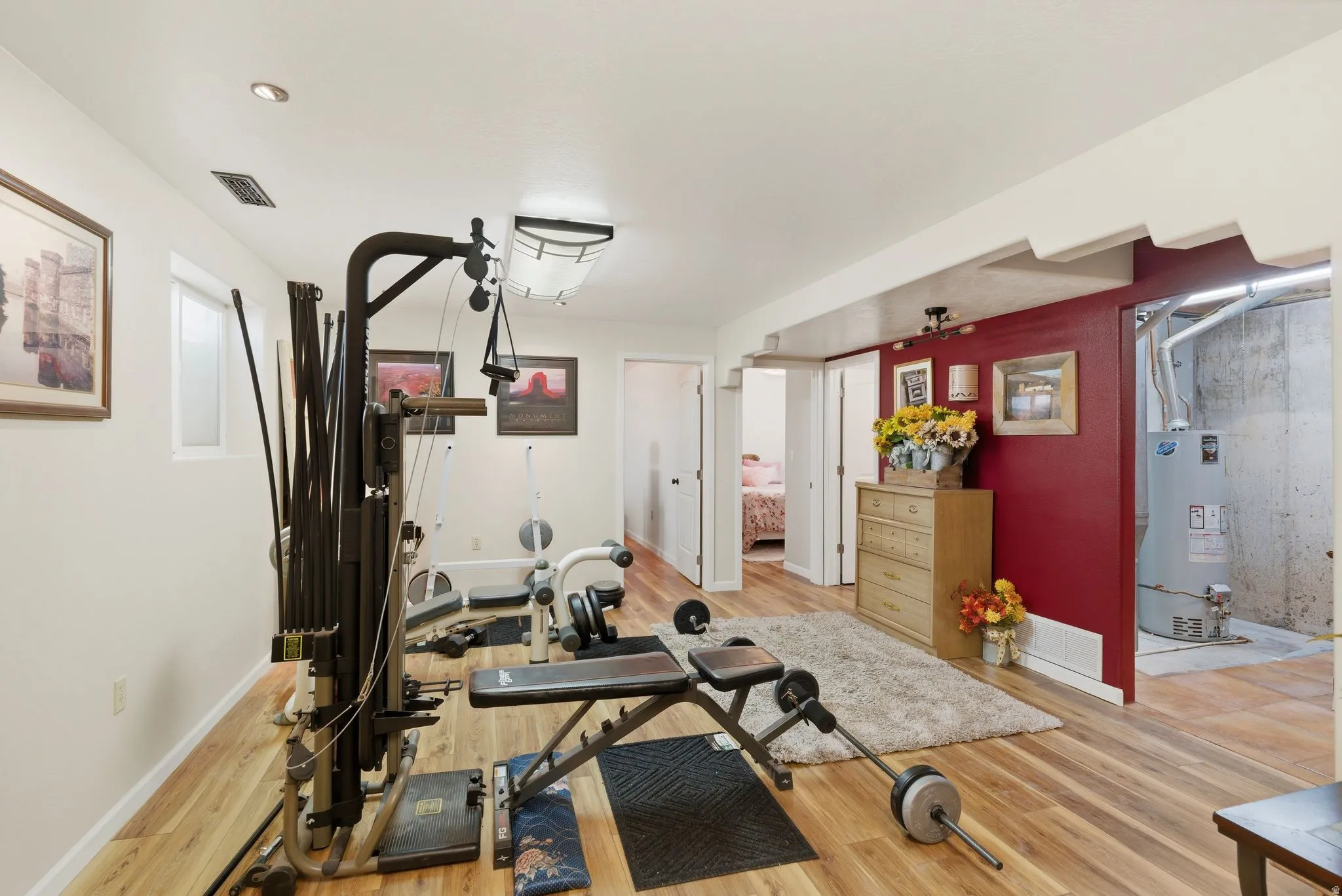 Workout room with gas water heater and light wood-style floors