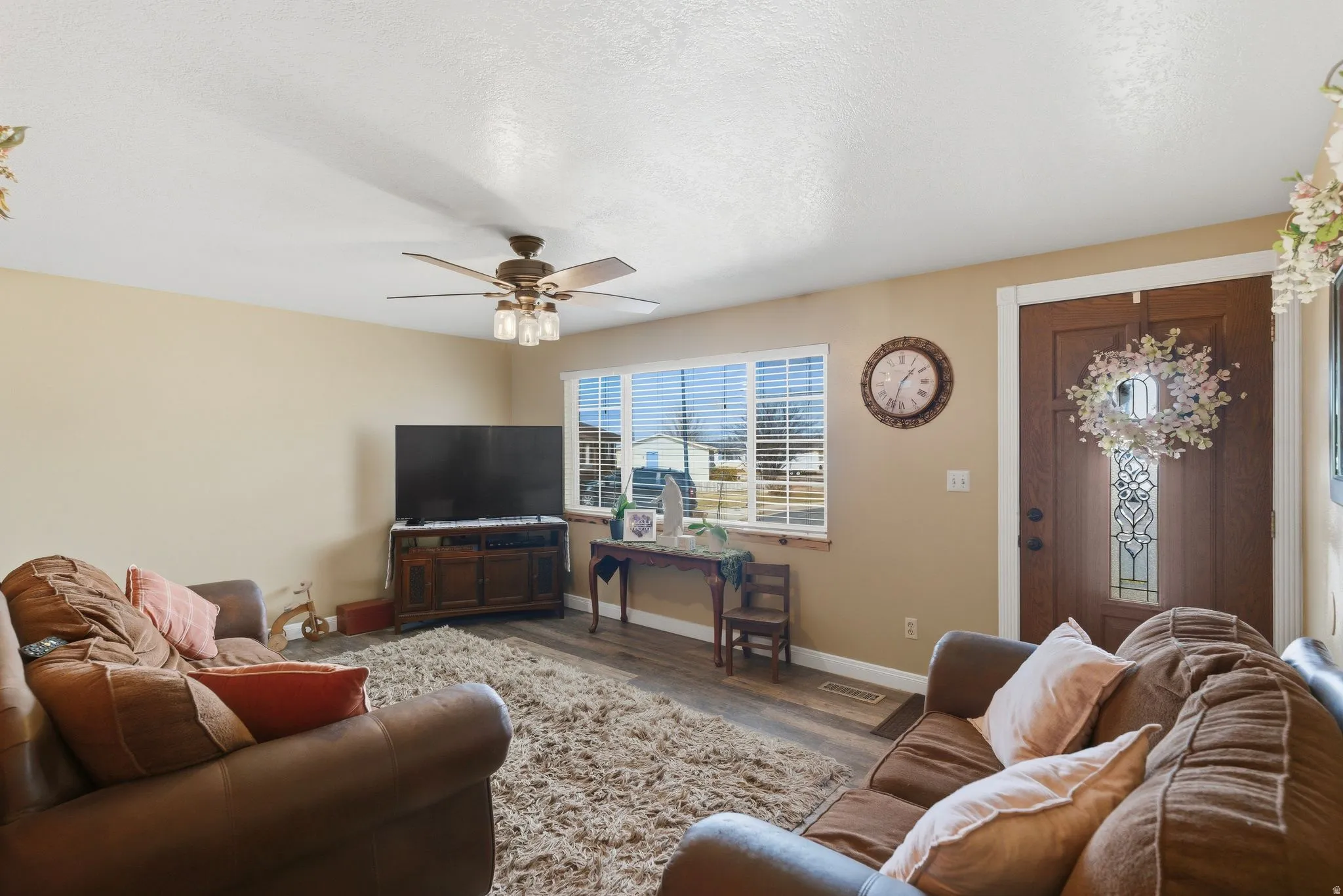 Living area with ceiling fan, wood finished floors, and a textured ceiling