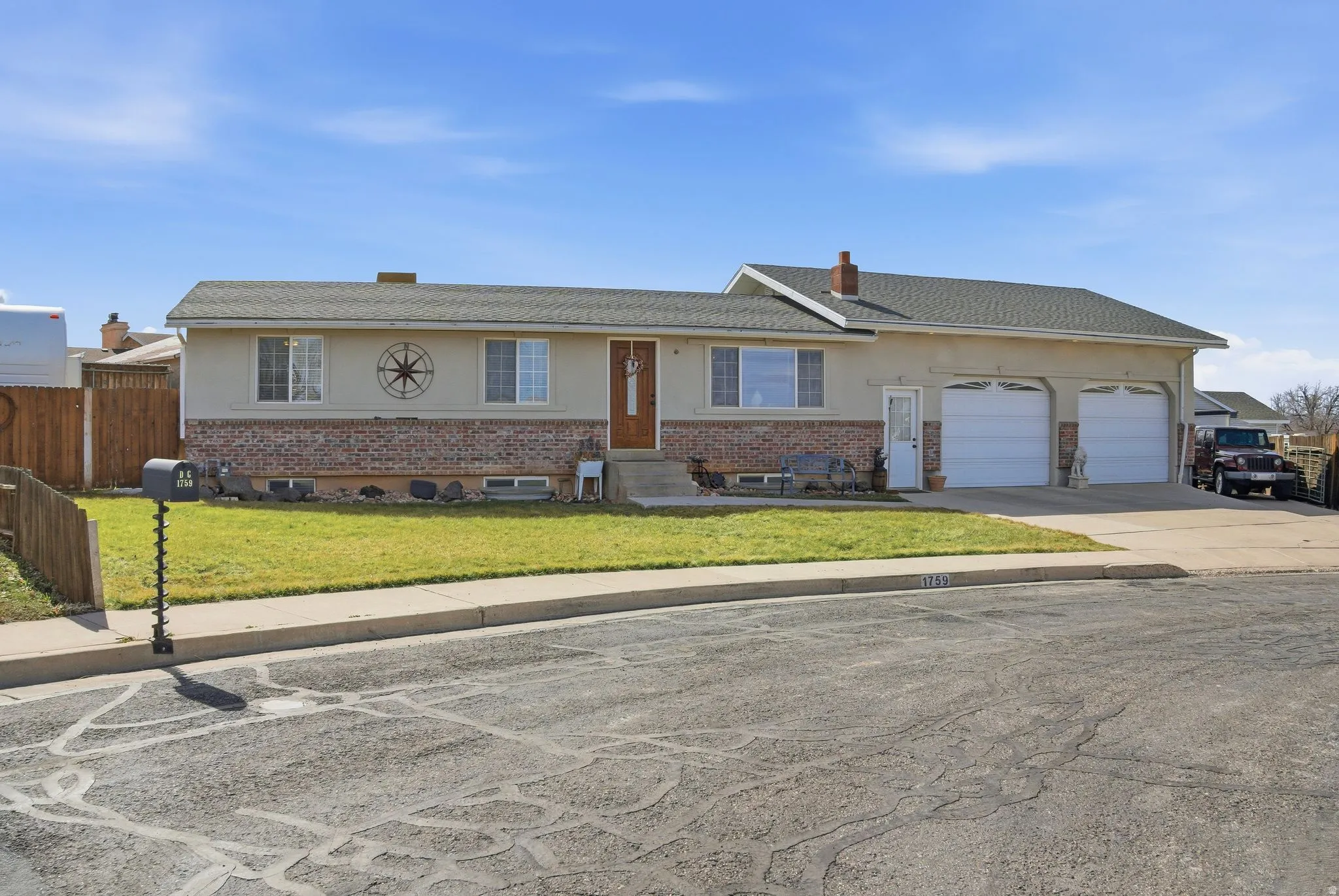Ranch-style home with stucco siding, concrete driveway, brick siding, an attached garage, and a chimney