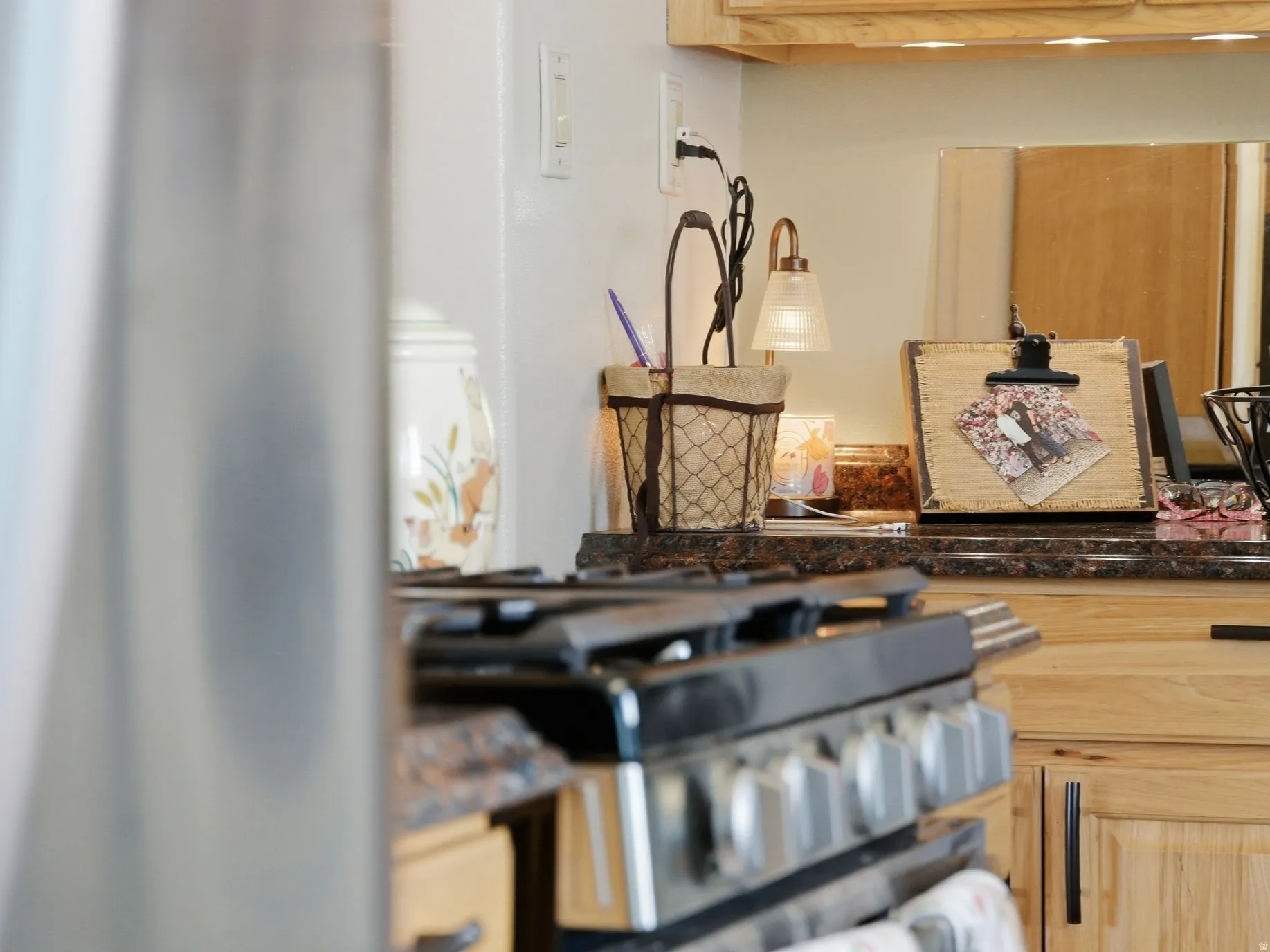 Kitchen view of light wood finish cabinetry, gas stove, and dark countertops