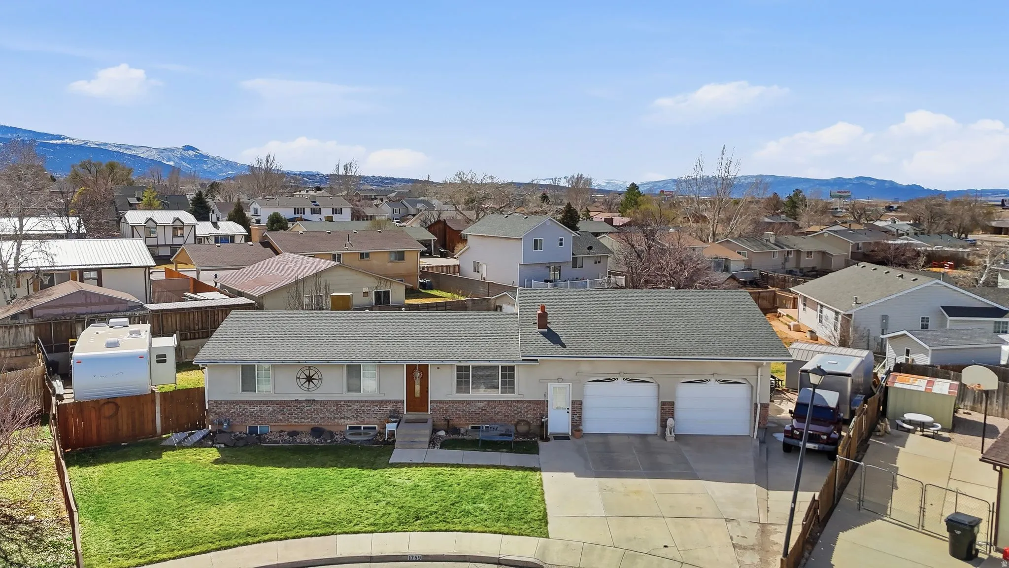 View of front facade featuring driveway, a residential view, a garage, brick siding, and a mountain view