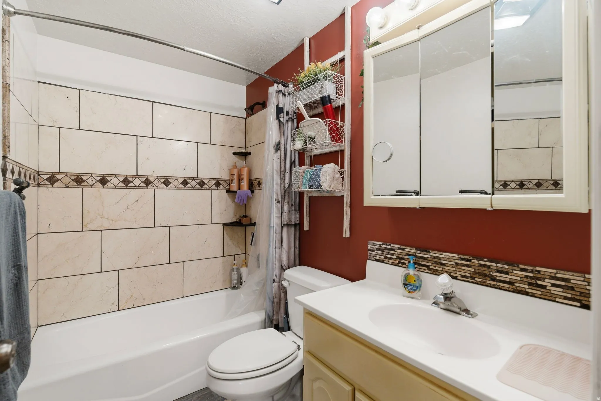 Bathroom with vanity, shower / bath combination with curtain, and tasteful backsplash