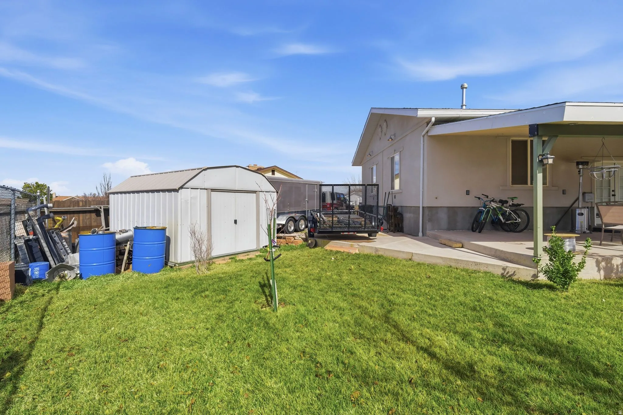 Fenced yard with a storage unit and a patio area