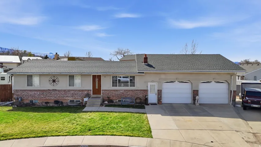 Ranch-style house featuring brick siding, concrete driveway, a garage, a front yard, and roof with shingles