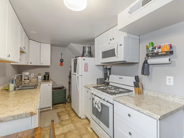 Kitchen with white appliances, white cabinets, and light countertops