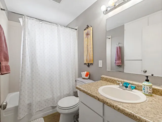 Bathroom with shower / bathtub combination with curtain, vanity, and dark wood-style floors