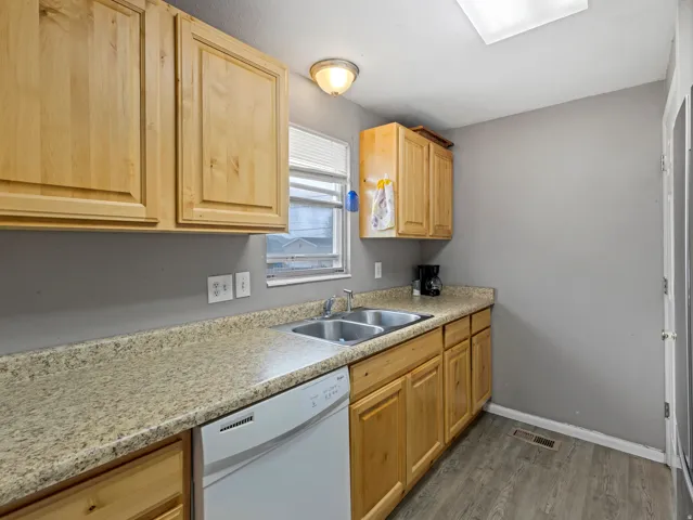 Kitchen with dishwasher, light countertops, dark wood-style floors, and light wood finish cabinets