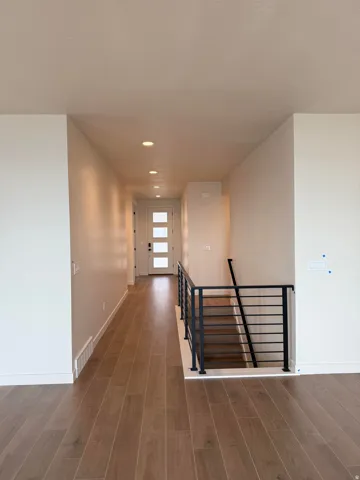 Hallway with dark wood-type flooring, an upstairs landing, and recessed lighting