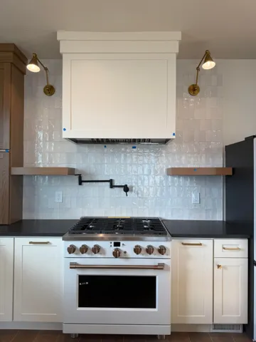 Kitchen with high end range, white cabinets, decorative backsplash, and open shelves