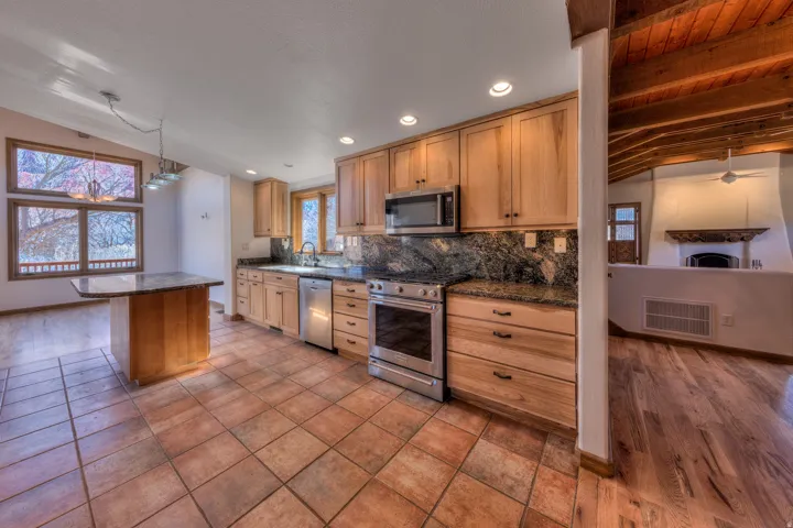 Kitchen with vaulted ceiling , granite countertops, stainless steel appliances, backsplash, and a center island w breakfast nook