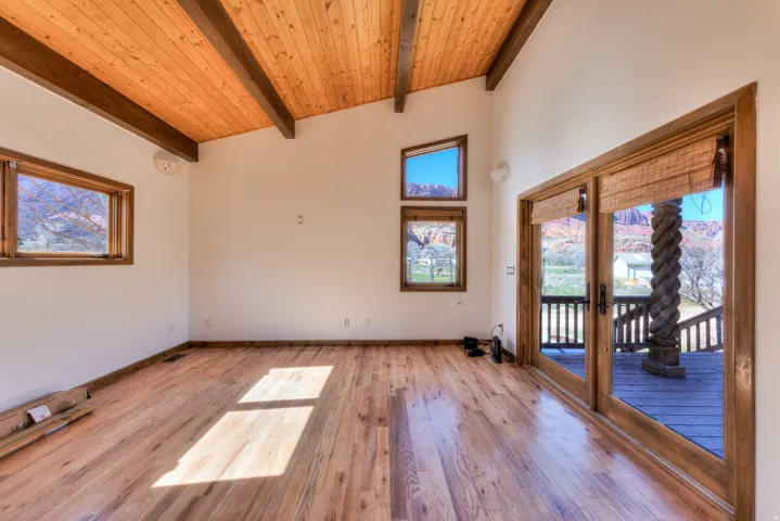 Spare room featuring French doors, a high wooden beamed ceiling, and oak wood flooring