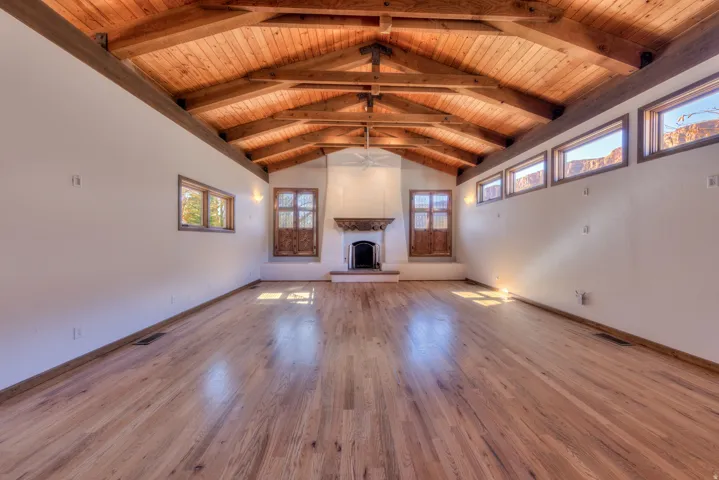 Open living area with oak floor and hand carved mantle.
