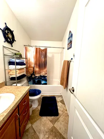 Bathroom with vanity, shower / tub combo with curtain, and a textured ceiling
