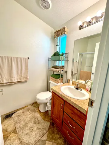 Bathroom featuring a stall shower, vanity, a textured ceiling, and a textured wall
