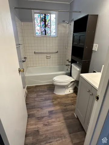 Wood-finish flooring, tiled bath surround, and a stained glass window