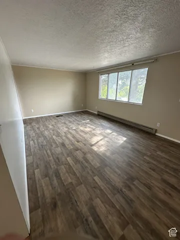 Spacious room featuring wood-finish flooring, neutral-toned walls, and a large window