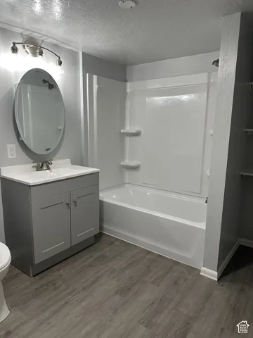 Renovated bathroom featuring a gray vanity with dual cabinet storage, white quartz countertop, and round mirror with integrated lighting