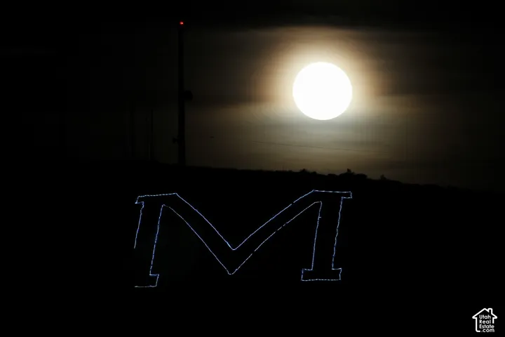 View from the dining room. A large letter "M" illuminated at night with a full moon and a radio tower in the background
