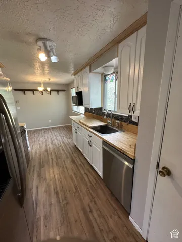 Kitchen featuring wood-finish flooring, white cabinetry, and wood-finish countertops
