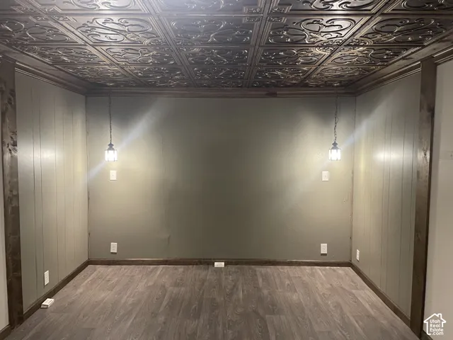 Basement Bedroom 3 featuring light wood-style floors, wood walls, and an ornate ceiling