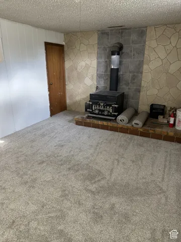 Basement living room, brand new carpet Wood-burning stove with a brick hearth, set against a stone-clad accent wall