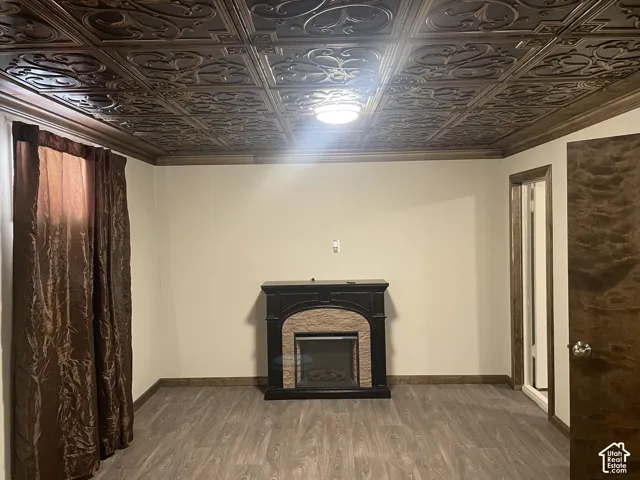Basement Bedroom 3 featuring wood finished floors, a fireplace, an ornate ceiling, and ornamental molding
