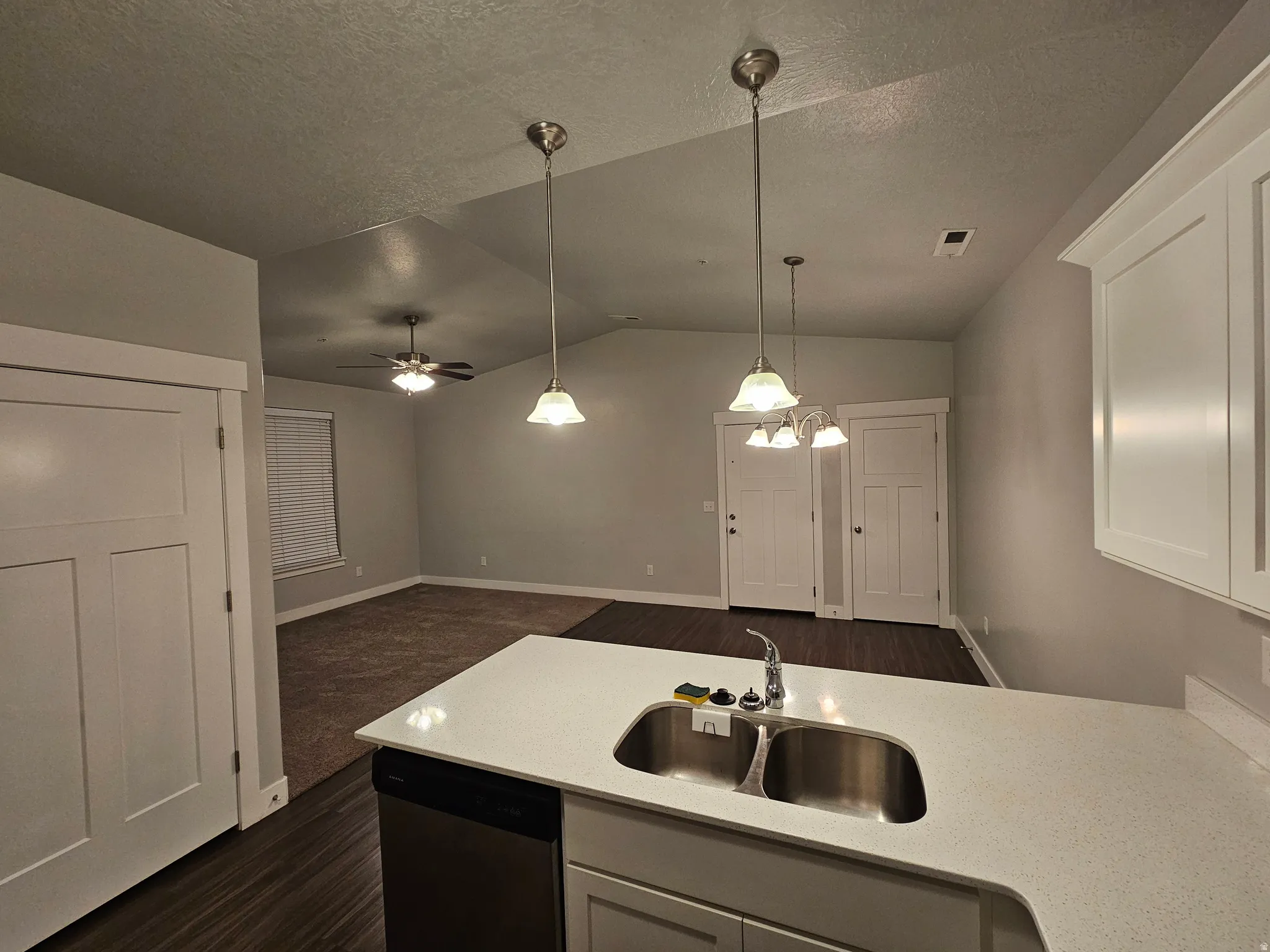 Kitchen featuring stainless steel dishwasher, ceiling fan, open floor plan, a textured ceiling, and dark wood finished floors