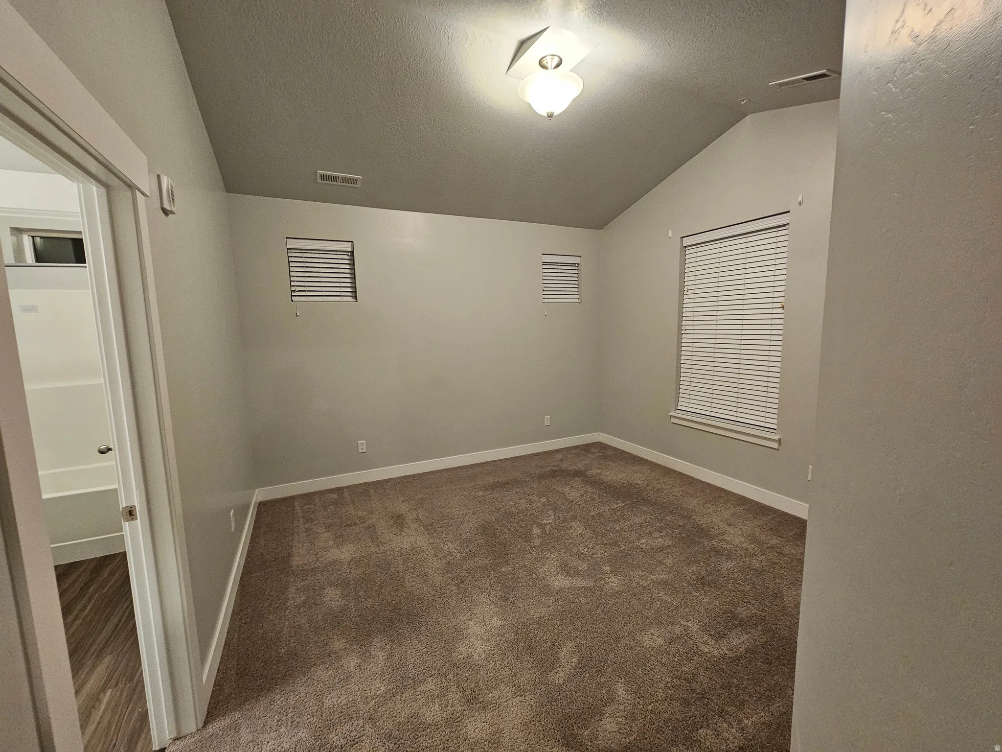 Unfurnished room with baseboards and dark colored carpet