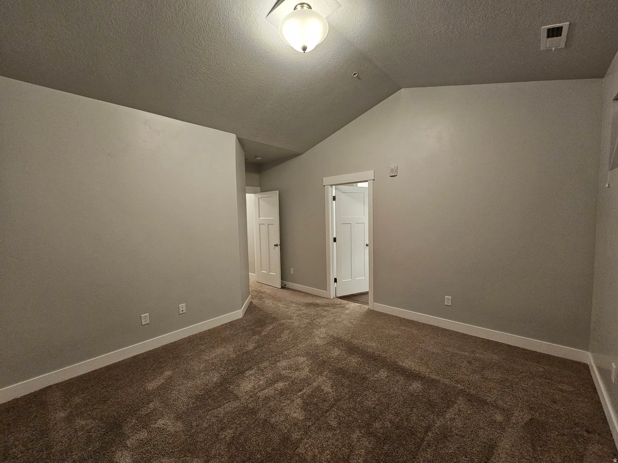 Empty room with dark colored carpet and baseboards