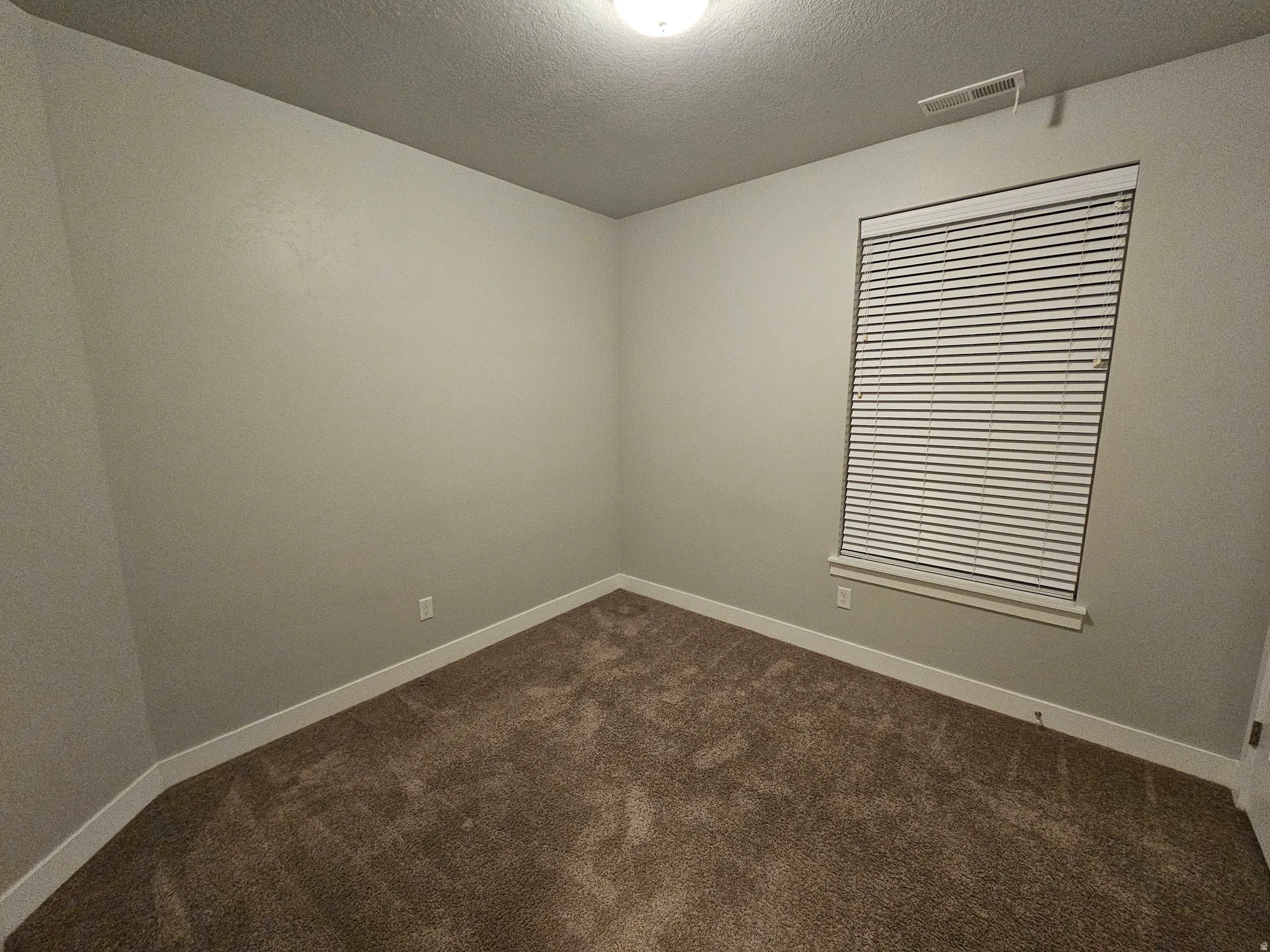 Unfurnished room with dark carpet and a textured ceiling