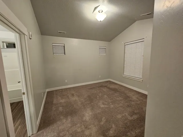 Unfurnished room with baseboards and dark colored carpet