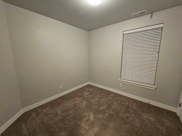 Unfurnished room with dark carpet and a textured ceiling
