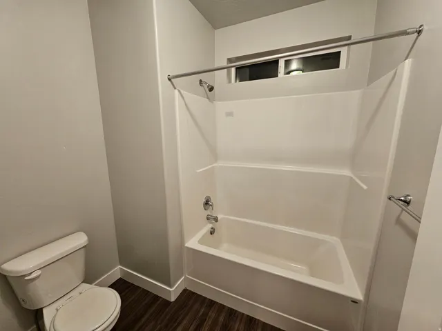 Bathroom featuring washtub / shower combination and dark wood-type flooring